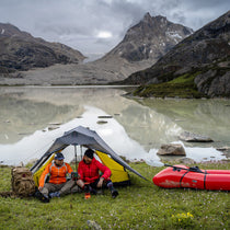 The Free Spirits Vista Tent in Rock Gray by an alpine lake, two campers seated in front with a red kayak.