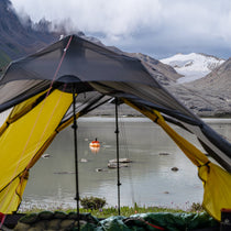 The Free Spirits Vista Tent viewed from the inside, looking out at a kayaker on a glacial alpine lake.