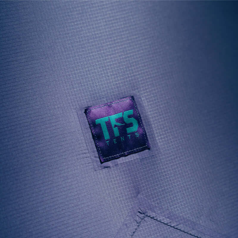 Close-up of the TFS logo patch on the purple ripstop fabric of a Stars 4 tent.